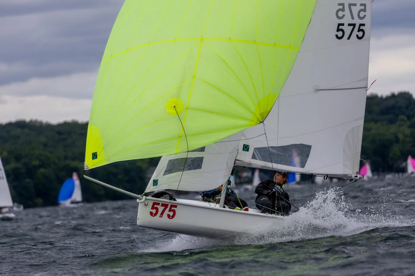 A one-design keelboat, number 575, sailing hard upwind